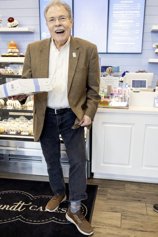 Peachtree Corners Mayor Mike Mason holding a cake box at the Nothing Bundt Cakes opening
