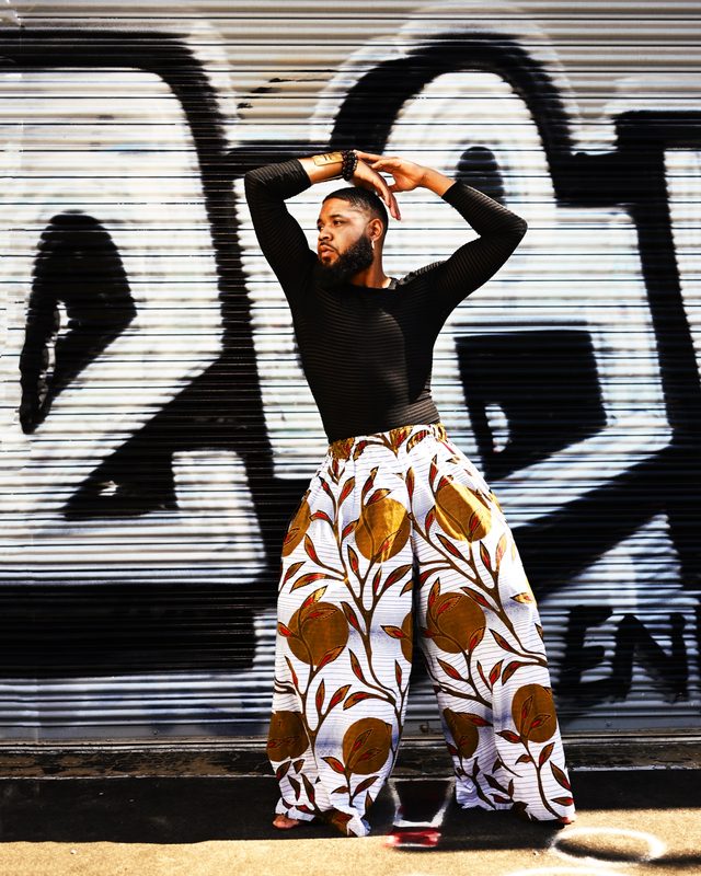 Justin Riley in a menswear look against street graffiti